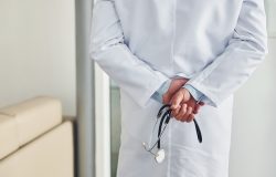 Stethoscope in hands. Professional medic in white coat is in the clinic